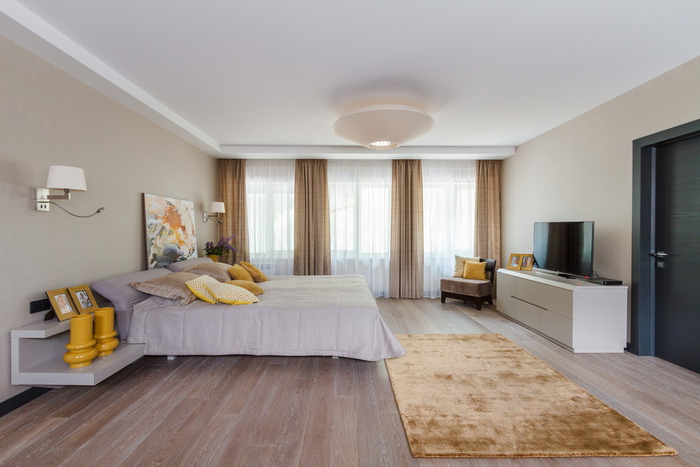 Large contemporary master bedroom in Other with beige walls, painted wood floors and beige floor.