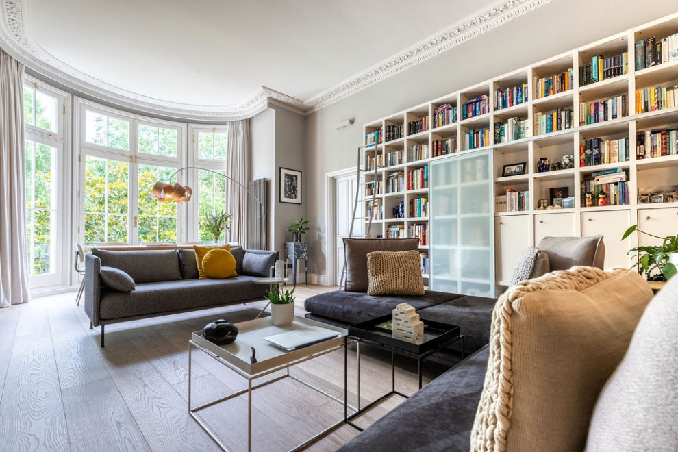 Immagine di un grande soggiorno chic con pareti grigie, parquet chiaro, TV a parete e pavimento marrone