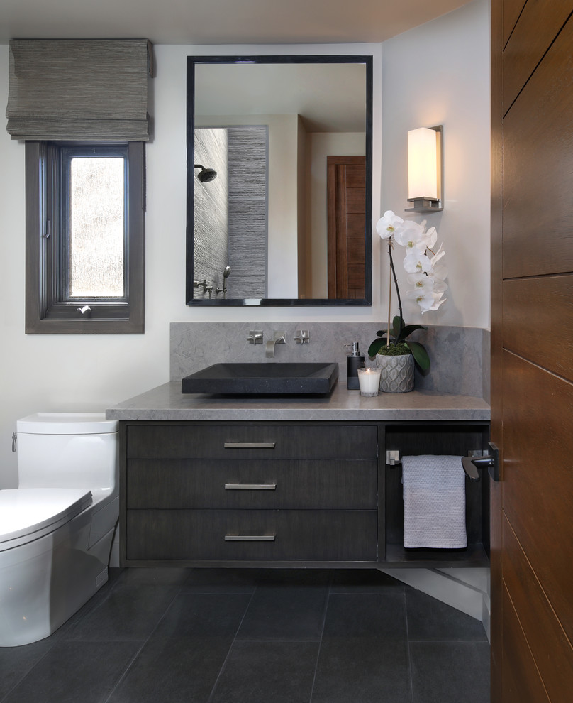 Photo of a mid-sized contemporary powder room in Orange County with flat-panel cabinets, grey cabinets, a one-piece toilet, white tile, porcelain tile, white walls, ceramic floors, a vessel sink, engineered quartz benchtops and black floor.