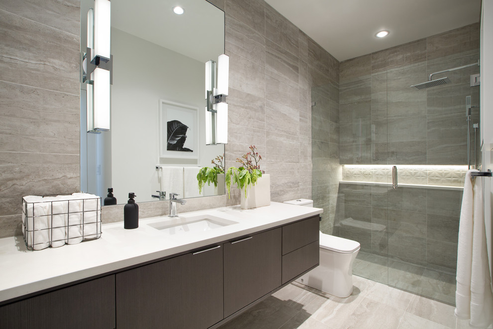 Inspiration for a small contemporary 3/4 bathroom in Vancouver with flat-panel cabinets, a curbless shower, a one-piece toilet, porcelain tile, ceramic floors, an undermount sink, engineered quartz benchtops, grey floor, a hinged shower door, white benchtops, grey cabinets, gray tile and a niche.