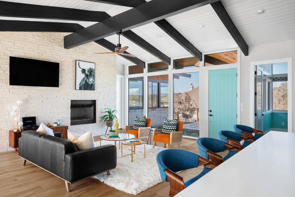 Immagine di un soggiorno minimalista di medie dimensioni e aperto con pareti bianche, parquet chiaro, cornice del camino in pietra, TV a parete e pavimento beige