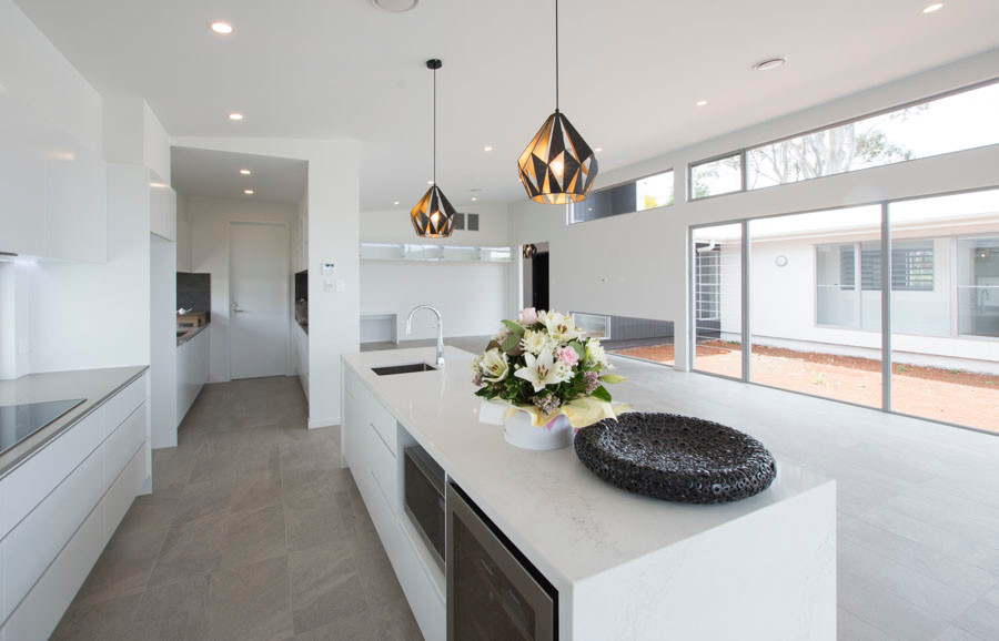 Inspiration for a mid-sized contemporary galley open plan kitchen in Brisbane with an undermount sink, white cabinets, quartz benchtops, black splashback, glass sheet splashback, stainless steel appliances, porcelain floors and with island.