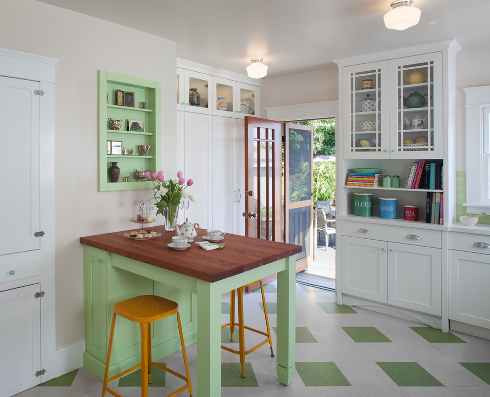 Mid-sized traditional l-shaped eat-in kitchen in San Diego with recessed-panel cabinets, white cabinets, green splashback, glass tile splashback, a farmhouse sink, solid surface benchtops, stainless steel appliances, green floor and linoleum floors.