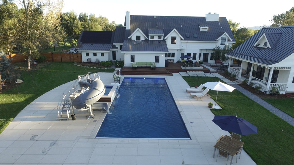 Photo of an expansive country backyard rectangular lap pool in Denver with a hot tub and concrete pavers.