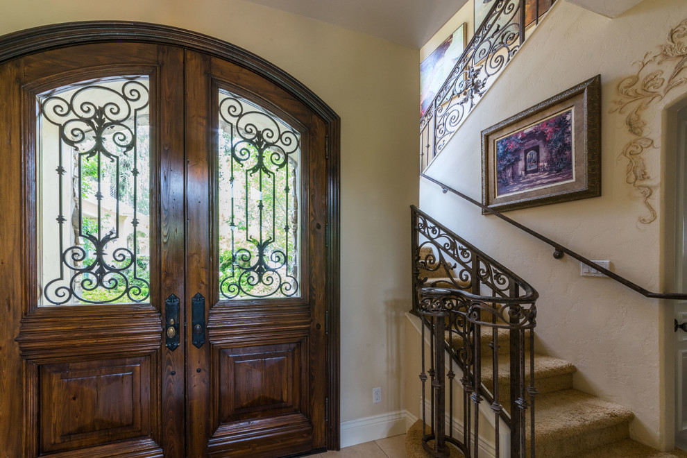 Large tuscan travertine floor front door photo with beige walls and a dark wood front door