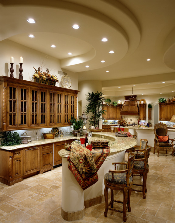 Open concept kitchen - huge transitional l-shaped travertine floor open concept kitchen idea in Phoenix with a drop-in sink, raised-panel cabinets, medium tone wood cabinets, granite countertops, beige backsplash, stone tile backsplash, paneled appliances and an island