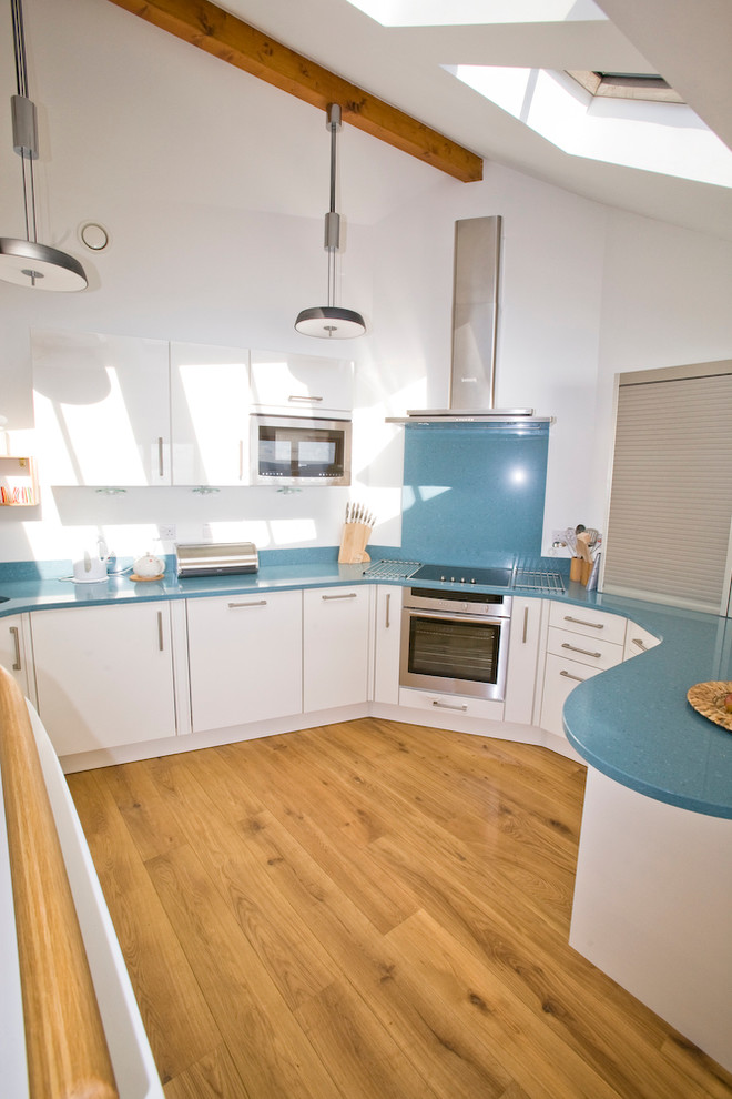 Inspiration for a beach style u-shaped eat-in kitchen in Cornwall with an undermount sink, flat-panel cabinets, white cabinets, quartzite benchtops, blue splashback, stone slab splashback, stainless steel appliances and blue benchtop.