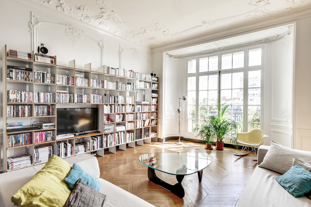This is an example of a transitional living room in Paris with white walls, medium hardwood floors and a freestanding tv.