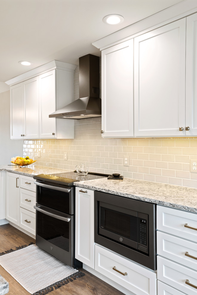 Eat-in kitchen - mid-sized transitional galley brown floor eat-in kitchen idea with an undermount sink, shaker cabinets, white cabinets, quartz countertops, ceramic backsplash and black appliances