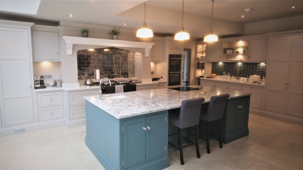 Inredning av ett klassiskt stort flerfärgad flerfärgat kök, med en undermonterad diskho, skåp i shakerstil, blå skåp, marmorbänkskiva, flerfärgad stänkskydd, stänkskydd i marmor, rostfria vitvaror, kalkstensgolv, en köksö och beiget golv