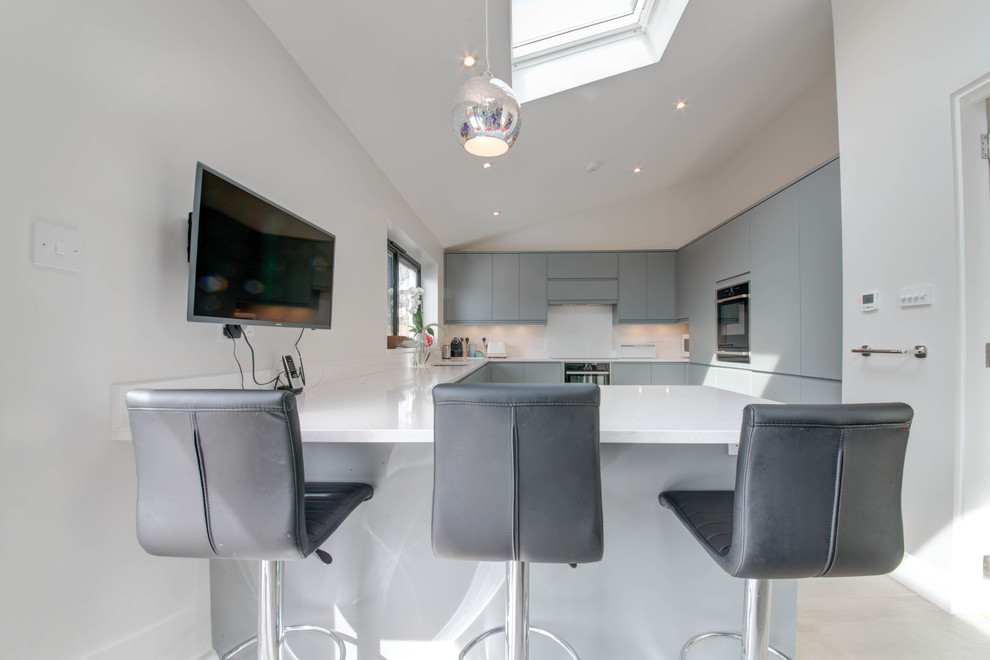 Photo of a large contemporary u-shaped eat-in kitchen in Surrey with flat-panel cabinets, grey cabinets, granite benchtops, white benchtop, an undermount sink, white splashback, porcelain splashback, stainless steel appliances, travertine floors and beige floor.