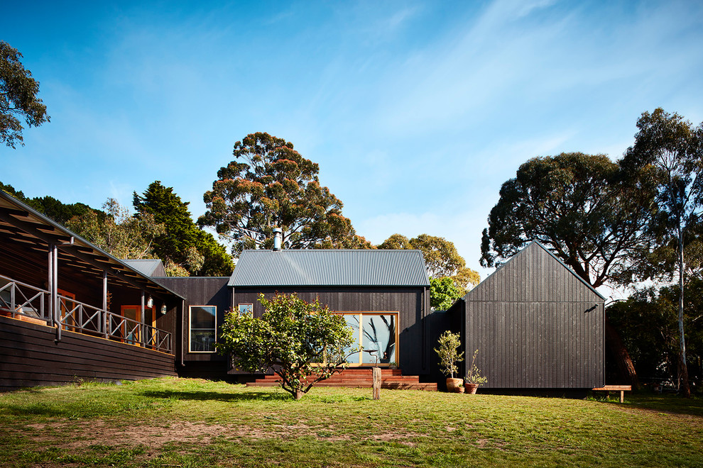 Photo of a mid-sized contemporary split-level black house exterior in Melbourne with mixed siding, a gable roof and a metal roof.