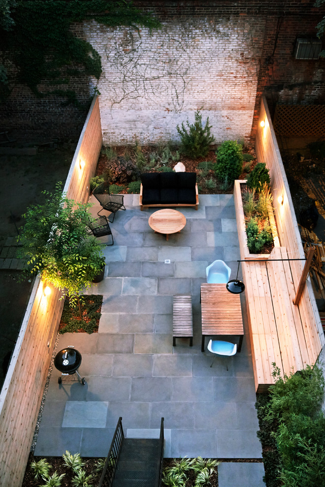 This is an example of a small contemporary backyard patio in New York with no cover and natural stone pavers.