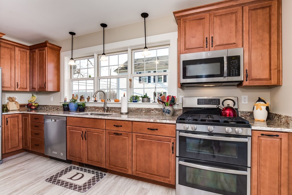 Inspiration for a mid-sized country u-shaped eat-in kitchen in Providence with an undermount sink, raised-panel cabinets, brown cabinets, granite benchtops, beige splashback, stainless steel appliances, vinyl floors, a peninsula and grey floor.