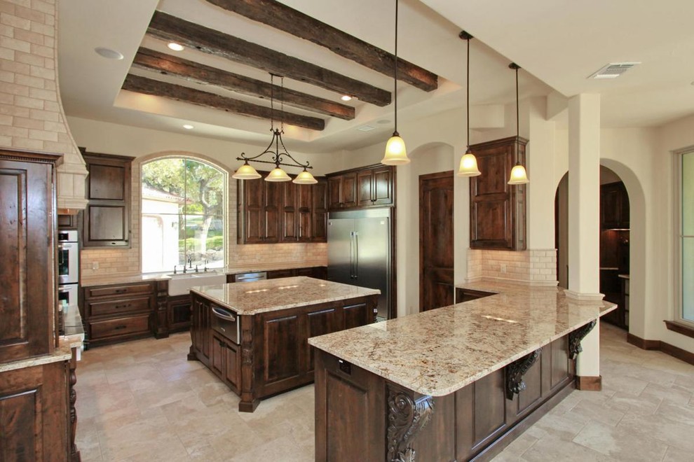 Inspiration for a traditional u-shaped separate kitchen in Austin with a farmhouse sink, raised-panel cabinets, dark wood cabinets, granite benchtops, beige splashback, stainless steel appliances and multiple islands.