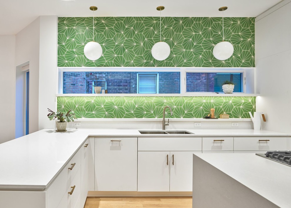 This is an example of a large scandinavian l-shaped separate kitchen in Toronto with a double-bowl sink, flat-panel cabinets, white cabinets, green splashback, light hardwood floors, with island, white benchtop, solid surface benchtops, panelled appliances and brown floor.