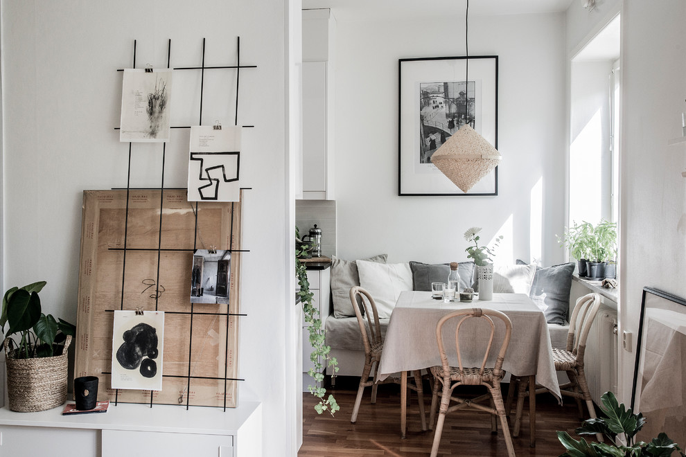 Scandinavian dining room in Stockholm with white walls, medium hardwood floors and brown floor.
