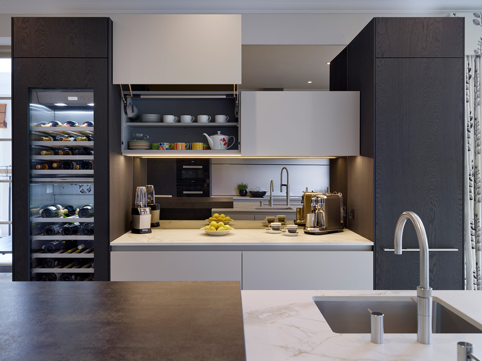 Mid-sized contemporary eat-in kitchen in Other with an integrated sink, flat-panel cabinets, dark wood cabinets, solid surface benchtops, black appliances, with island and metallic splashback.
