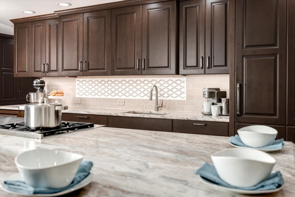 Huge transitional l-shaped medium tone wood floor and brown floor open concept kitchen photo in Seattle with an undermount sink, raised-panel cabinets, brown cabinets, quartzite countertops, beige backsplash, porcelain backsplash, stainless steel appliances, an island and multicolored countertops