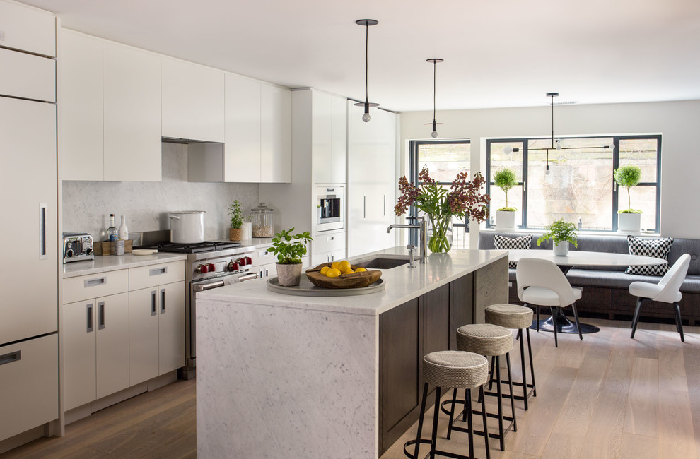 Inspiration for a contemporary galley eat-in kitchen in Boston with flat-panel cabinets, marble benchtops, stainless steel appliances, light hardwood floors, with island, an undermount sink, white cabinets and white splashback.