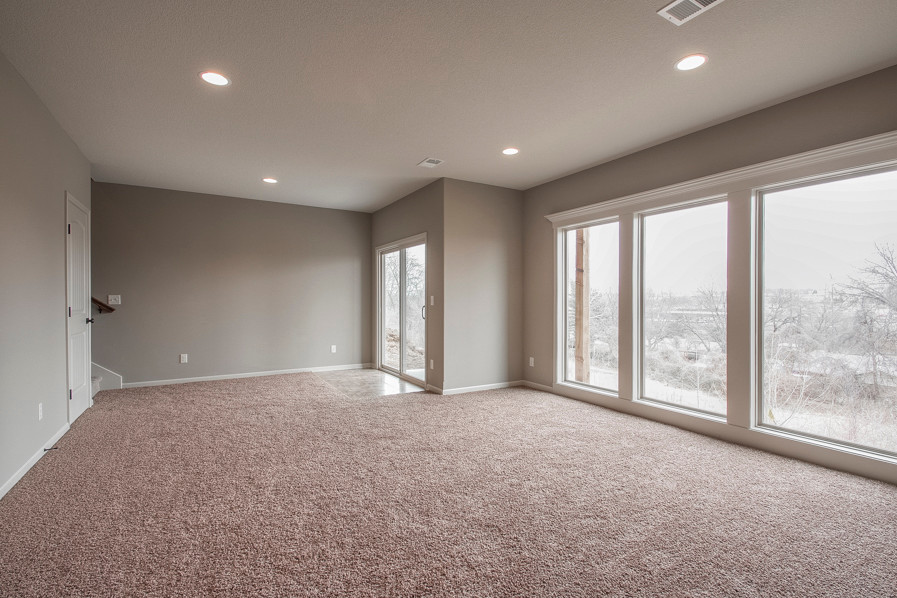 This is an example of a large traditional walk-out basement in Kansas City with grey walls and carpet.