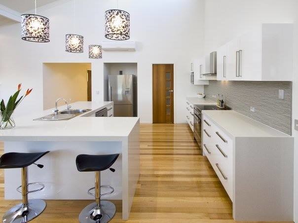 Design ideas for a modern l-shaped eat-in kitchen in Brisbane with a double-bowl sink, white cabinets, granite benchtops, metallic splashback, glass tile splashback, stainless steel appliances, bamboo floors and multiple islands.