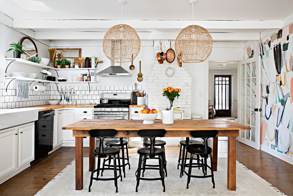 Inspiration for an eclectic l-shaped eat-in kitchen in Nashville with a farmhouse sink, recessed-panel cabinets, white cabinets, wood benchtops, white splashback, stainless steel appliances and dark hardwood floors.