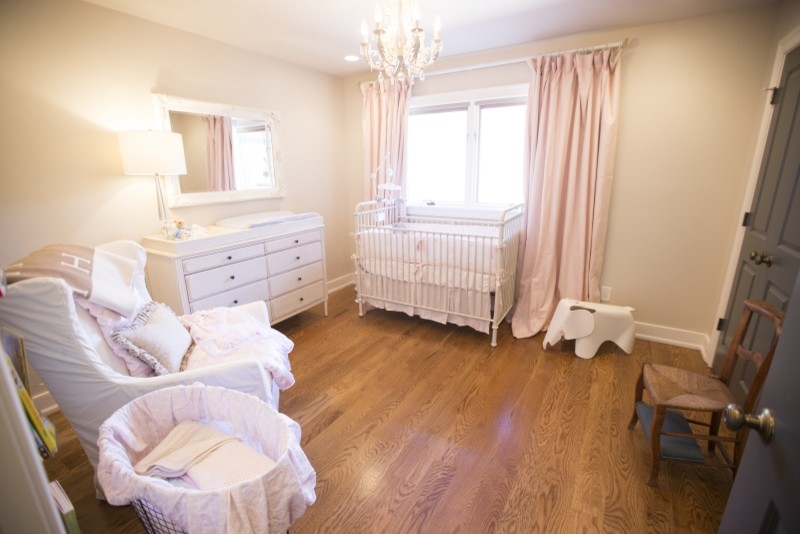This is an example of a mid-sized transitional nursery for girls in Louisville with beige walls and medium hardwood floors.