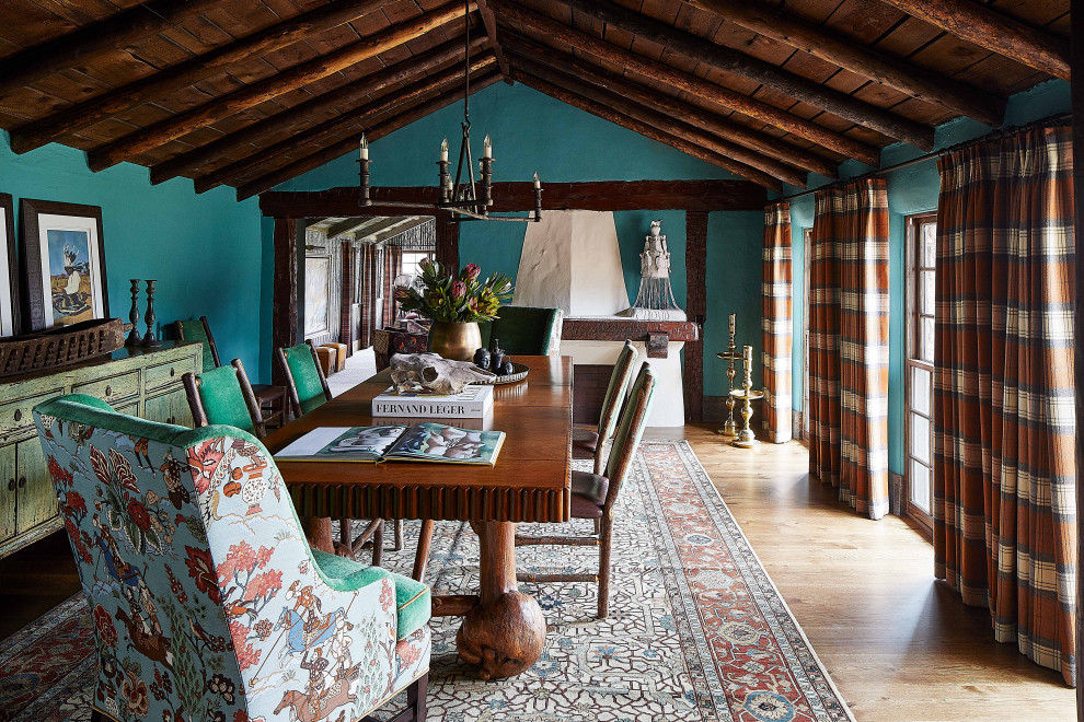Foto di una sala da pranzo aperta verso la cucina stile rurale con pareti blu, parquet chiaro, soffitto a volta, pavimento marrone e camino classico