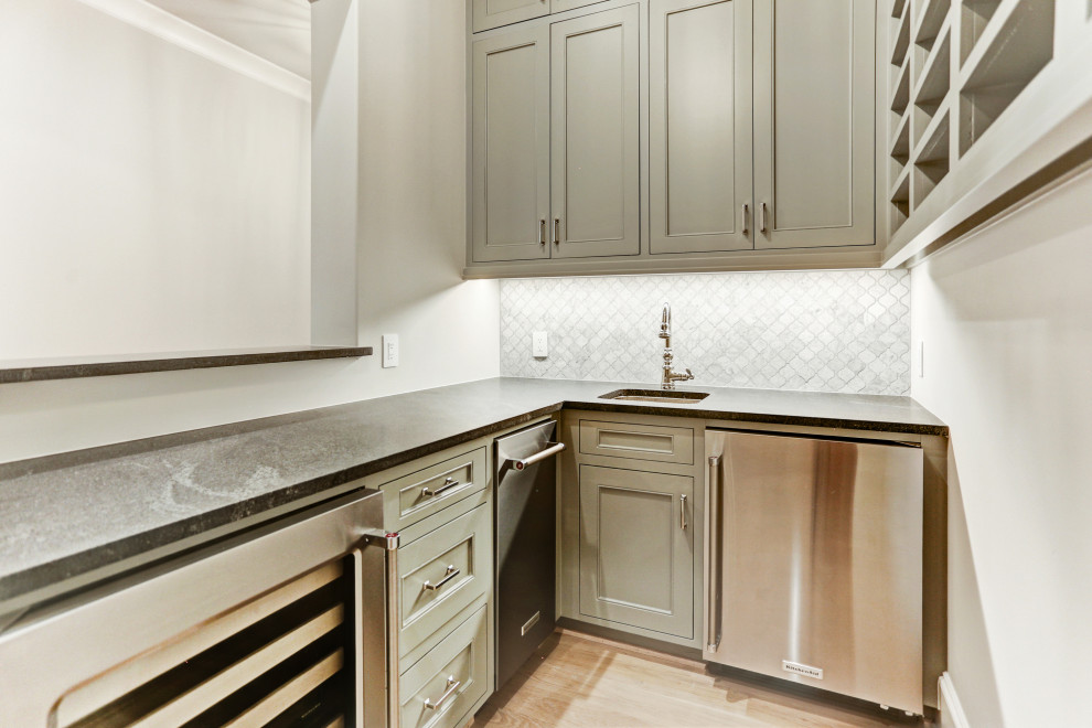 Example of a mid-sized french country l-shaped light wood floor and beige floor wet bar design in Houston with an undermount sink, recessed-panel cabinets, green cabinets, gray backsplash and mosaic tile backsplash