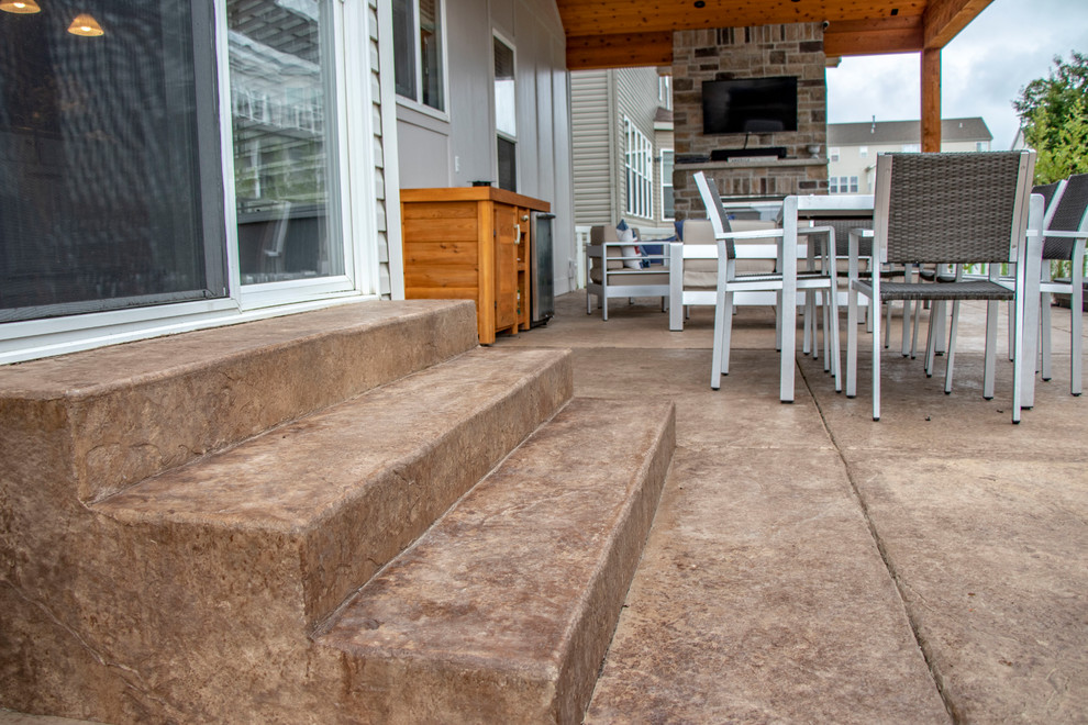 Photo of a mid-sized backyard patio in St Louis with with fireplace, stamped concrete and a roof extension.
