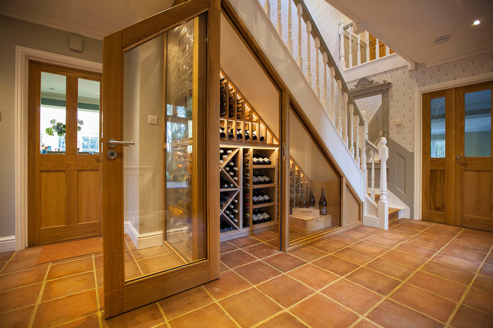 This is an example of a small traditional wine cellar in Essex with terra-cotta floors, orange floor and diamond bins.