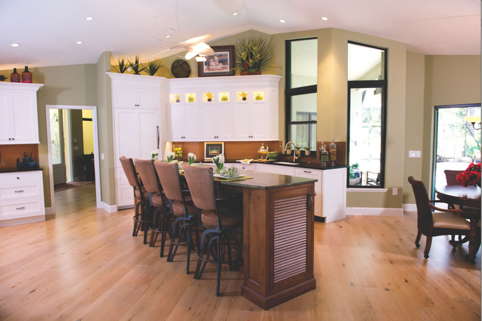 Inspiration for a large transitional l-shaped light wood floor and brown floor eat-in kitchen remodel in Tampa with an undermount sink, shaker cabinets, white cabinets, granite countertops, brown backsplash, glass sheet backsplash, paneled appliances and an island