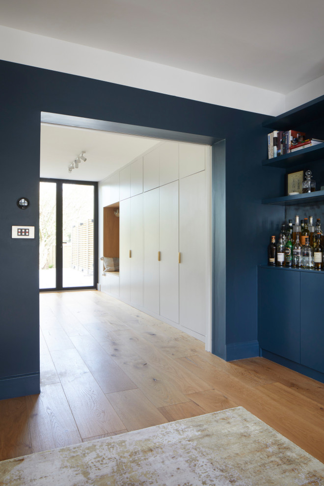 ロンドンにある高級な広いコンテンポラリースタイルのおしゃれな独立型リビング (青い壁、無垢フローリング、標準型暖炉、木材の暖炉まわり、マルチカラーの床) の写真