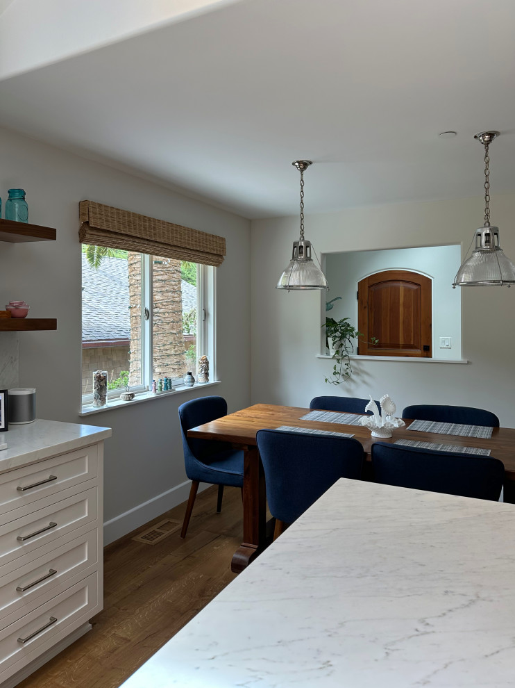 Esempio di una sala da pranzo aperta verso la cucina classica di medie dimensioni con pareti bianche, pavimento in legno massello medio e pavimento marrone
