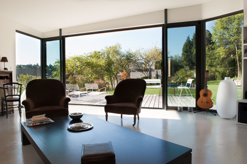 Idées déco pour une grande salle de séjour contemporaine ouverte avec sol en béton ciré, une cheminée double-face et un manteau de cheminée en plâtre.