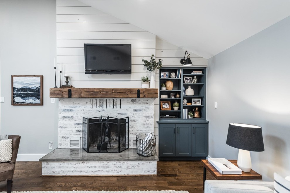Design ideas for a mid-sized country open concept living room in Dallas with grey walls, medium hardwood floors, a standard fireplace, a brick fireplace surround, a wall-mounted tv and brown floor.