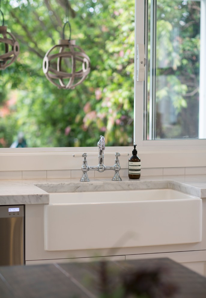Photo of a large traditional u-shaped eat-in kitchen in Sydney with a drop-in sink, shaker cabinets, white cabinets, quartz benchtops, white splashback, ceramic splashback, stainless steel appliances, light hardwood floors, no island and beige floor.