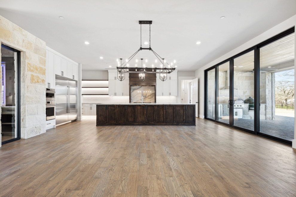 Design ideas for a large modern l-shaped eat-in kitchen in Dallas with an undermount sink, flat-panel cabinets, white cabinets, granite benchtops, white splashback, subway tile splashback, stainless steel appliances, medium hardwood floors, with island, beige floor and grey benchtop.