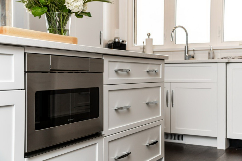 Mid-sized transitional l-shaped dark wood floor and brown floor open concept kitchen photo in Ottawa with an undermount sink, shaker cabinets, white cabinets, quartz countertops, white backsplash, subway tile backsplash, stainless steel appliances, an island and white countertops