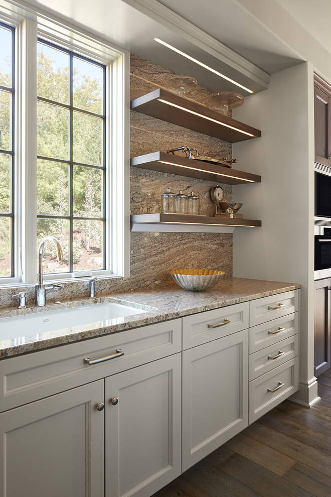 Kitchen pantry - large transitional medium tone wood floor kitchen pantry idea in Minneapolis with a single-bowl sink, flat-panel cabinets, white cabinets, granite countertops, beige backsplash, stone slab backsplash, paneled appliances and an island