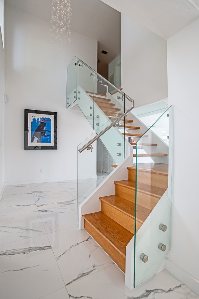 This is an example of a mid-sized modern wood l-shaped staircase in Tampa with open risers and glass railing.