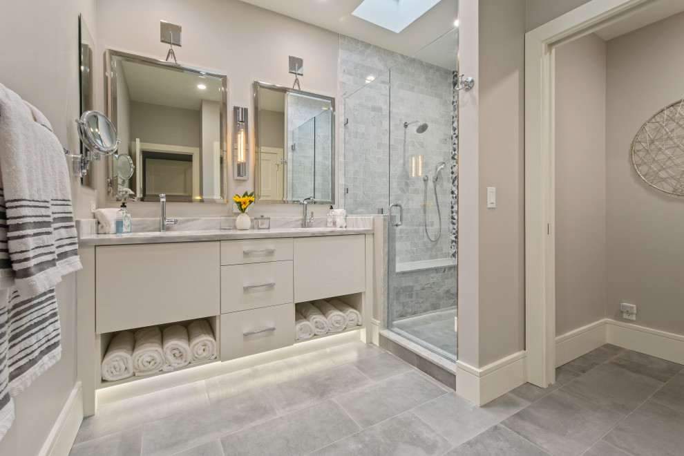 Photo of a large beach style master bathroom in Other with grey floor, flat-panel cabinets, beige cabinets, an alcove shower, gray tile, porcelain tile, beige walls, porcelain floors, a hinged shower door and grey benchtops.