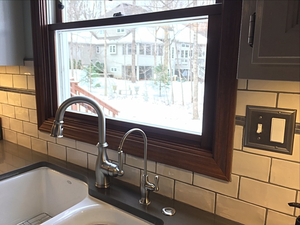 Mid-sized transitional u-shaped medium tone wood floor enclosed kitchen photo with an undermount sink, white cabinets, quartz countertops, white backsplash, subway tile backsplash, stainless steel appliances and an island