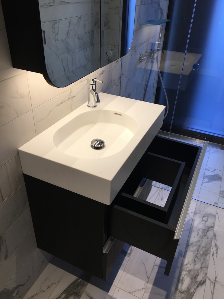 Small modern 3/4 bathroom in Sydney with flat-panel cabinets, black cabinets, a corner shower, a wall-mount toilet, gray tile, marble, grey walls, marble floors, a drop-in sink, solid surface benchtops, grey floor and a hinged shower door.