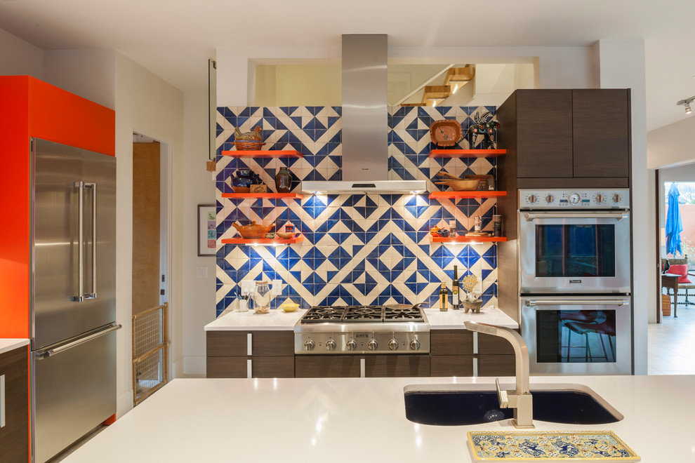 Contemporary l-shaped kitchen in Houston with an undermount sink, flat-panel cabinets, blue splashback, stainless steel appliances, with island, white benchtop and dark wood cabinets.