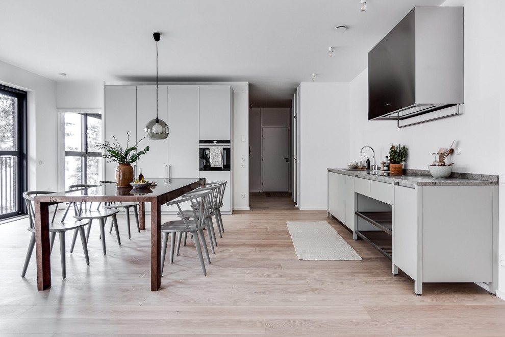 Expansive scandinavian l-shaped eat-in kitchen in Stockholm with an undermount sink, flat-panel cabinets, grey cabinets, panelled appliances, no island, beige floor and grey benchtop.