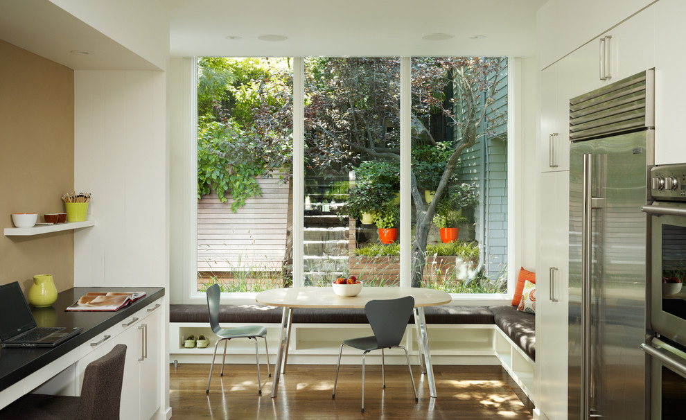 Photo of a transitional eat-in kitchen in San Francisco with stainless steel appliances, flat-panel cabinets and white cabinets.