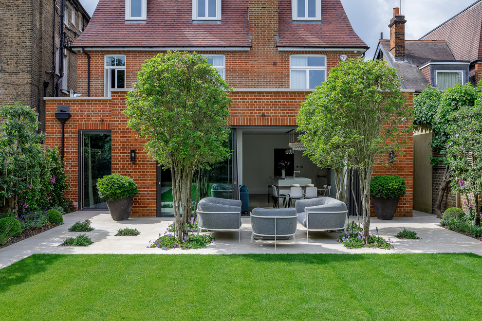 Large contemporary backyard formal garden in London with brick pavers.