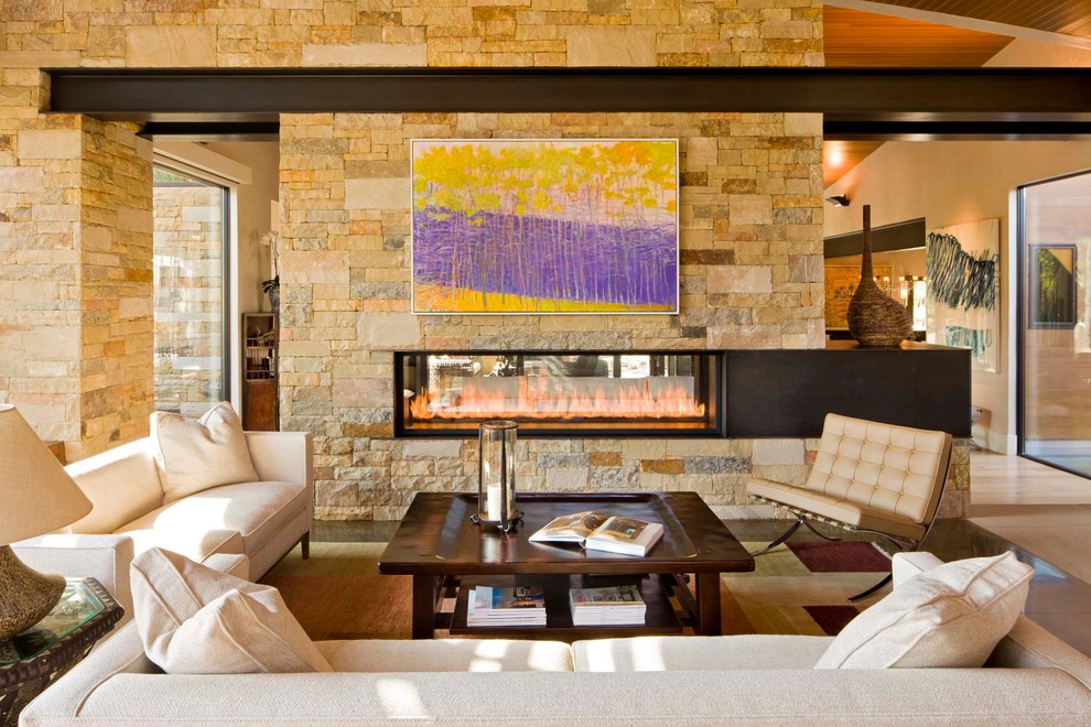 Photo of a contemporary living room in Denver with a two-sided fireplace and a stone fireplace surround.